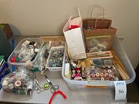 Overview of multiple containers and bags with sewing threads, notions, scissors, and crochet needles