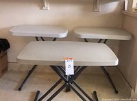 View of all three folding tables grouped together showing white tops and metal folding legs.