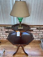 Full view of the two-tier hexagonal wooden table with the green textured glass lamp placed on the top tier.