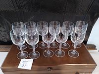 Eleven clear Bohemia red wine glasses grouped on a wooden box, showing their shape and size.