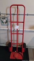 Full view of the red hand dolly with foot pump attached showing handle and hose