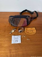 Full view of the entire lot on wooden surface including fanny pack, watches, coin purse, and earrings.