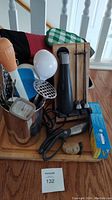 Photo showing an assortment of kitchen items including a wooden cutting board, metal utensil holder with various kitchen tools, Cuisinart electric cutting utensil, oven mitts, and a box of Ziploc portioning bags.