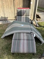 Two green/gray striped cushions with ties placed on a lounge chair, showing pattern and dimensions.