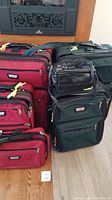 Photo of green and red three-piece luggage sets and two black handbags showing overall condition and size.