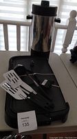 Photo of the electric coffee percolator, electric griddle, and four kitchen utensils on the griddle surface, showing overall lot contents.