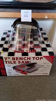 Stay Sharp 7 inch bench top tile saw boxed with face shield placed on top, showing the box graphics and product name.