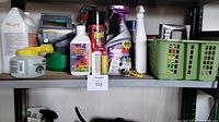 Shelf showing assorted insecticides, sprays, and yard pest control products including branded sprays such as Raid and SpiderBan, plus containers and bottles, some with spray triggers.