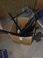 Box filled with black metal closet organizer tubes and parts