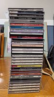 Stack of compact discs showing top titles including John Lennon, Grass Roots, Fleetwood Mac, Cream, and others.