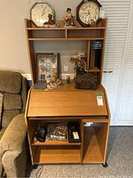 Front view of computer desk showing lifting top, hutch with storage, and lower compartments with items on and in the desk.