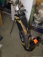 Full view of John Daly golf bag with clubs (irons and drivers) placed inside, showing stand support and placement in room.