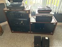 View of media cabinet with tinted glass doors housing electronics.