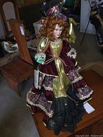 Full length photo of the porcelain doll seated on a wooden chair showing full dress and details
