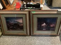 Photo showing both framed homestead night prints side by side, one with missing glass and loose frame, the other with intact glass and frame.
