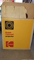 Photo of original yellow Kodak Carousel Projector box with Kodak logo and circular graphic