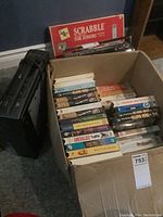 Box of assorted VHS tapes positioned next to a black Zenith VHS player.