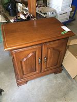 Front view of solid wood night stand showing double paneled doors with metal handles and beveled top surface