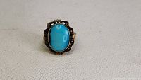 Front view of antique handmade turquoise ring on white cloth background