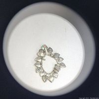 Top-down view of entire charm bracelet showing arrangement of heart-shaped charms and enamel piece