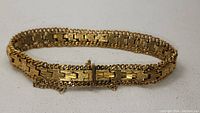 Handmade antique gold-tone bracelet showing detailed linked design and box clasp with safety chain.