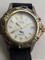 Close-up of the watch face showing the white dial, gold-tone hour markers, hands, date window, and rotating bezel with minute markers.