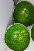 Set of 3 vintage aluminum bowls with green enamel interiors, two with radiating line texture and one with leaf-like pattern.