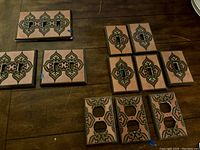 Multiple decorative ceramic plate covers laid out on a wooden surface showing 1 triple switch plate, 2 double switch plates, 5 single switch plates, and 3 double outlet covers with intricate design.