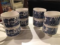 Set of eight blue and white ceramic tea cups stacked in pairs showing the repeated traditional Chinese landscape design.
