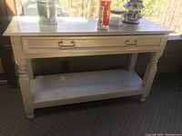 Photo of a repainted older wooden console table with a single drawer and bottom shelf, showing scratches and wear on the surface.