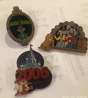 Group of three Disney collectible pins on paper background: 2006 Chip & Dale Cinderella Castle pin, Haunted Mansion ghost pin in frame, and Pirates of the Caribbean jail dog key pin.