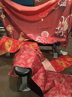 Large hanging red tapestry with a dragon and pink floral details, partially visible fabric folds shown in a basement setting