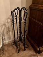 Handmade iron fireplace tool set standing assembled with holder and tools hanging