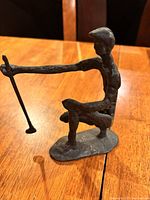 Side view of metal golfer figurine in crouching position holding golf club.