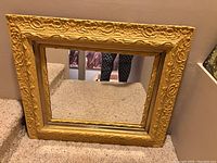 Front view of the large square yellow wall mirror showing intricate and decorative carved trim with noticeable wear.