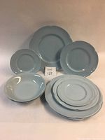 Full view of the set including three dinner plates, three salad plates, two small plates, and two soup bowls, all in blue-gray color with scalloped edges.