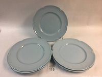 Stack of 9 light blue-grey scalloped edge dinner plates shown flat and propped to display shape and color.