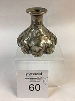 Front view of the lobed perfume bottle showing silver overlay floral motif and smooth finish.