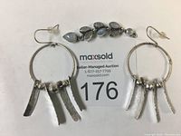 Pair of sterling silver earrings with hammered silver rectangular dangles and silver beads, displayed alongside a silver pendant with moonstones.