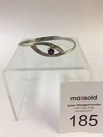 Sterling silver swing bracelet displayed on clear stand showing front and amethyst gemstone.