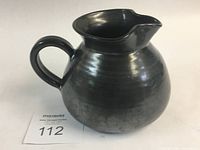 Black metallic glazed ceramic milk jug, side view showing rounded belly and handle