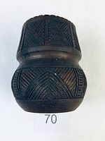 Front view of the dark brown pottery vase showing geometric incised patterns on upper and lower bands.