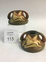 Front and side angled view of one Zephyr Lily candlestick holder showing raised lily flower and two small handles.