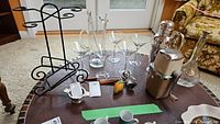 Photo of entire barware set including glasses, pitcher, wine caddy, stirrer, ice crusher, cocktail shakers, and decorative bottle.