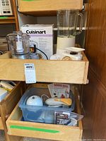 Cuisinart chopper/grinder, KitchenAid blender, and Thunderstick handheld mixer in wooden drawers. Cuisinart box visible behind chopper.
