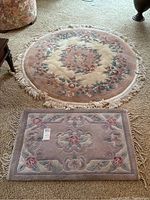 Photo of round and rectangular floral patterned carpets on beige carpeted floor, showing size and design clearly