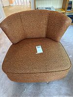 Front view of mid-century modern style orange-brown upholstered swivel chair showing the rounded backrest and seat cushion.