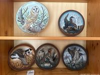 Photo of six Wildlife Society collector plates showing birds and waterfowl in natural settings on wooden shelf