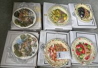 Six Davenport Studios collector plates in individual boxes wrapped in plastic, displaying diverse cottage and fruit basket designs.