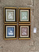 Four framed porcelain wall artworks arranged in a group on carpeted floor showing different background colors and relief designs